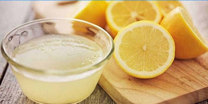 Succo di limone in una ciotola e mezzo limoni