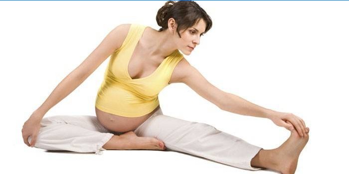 Ragazza incinta che fa allungando esercizio