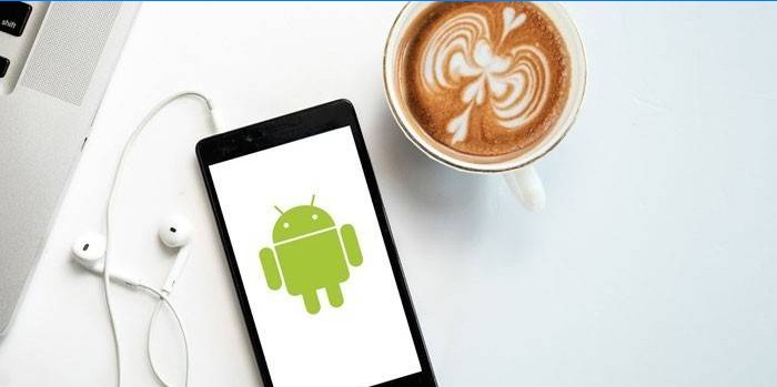 Smartphone con cuffie e una tazza di caffè.