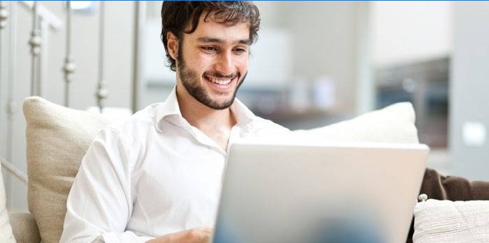 Un uomo si siede su un divano con un computer portatile