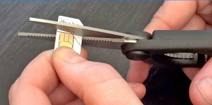 Un uomo taglia una carta SIM in base al modello con le forbici