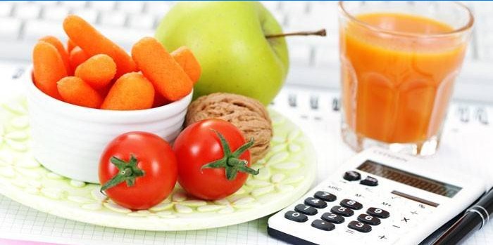 Frutta, verdura, un bicchiere di succo e una calcolatrice
