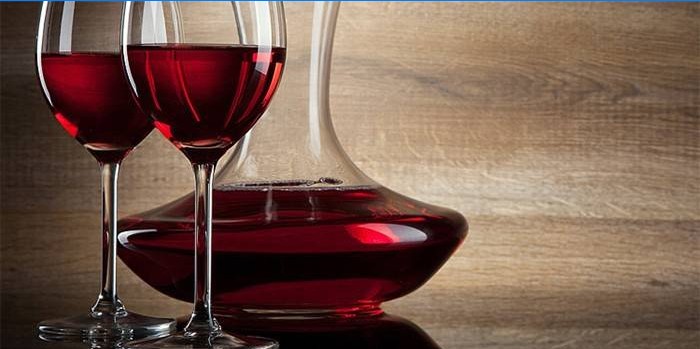Due bicchieri di vino e un contenitore di vino rosso