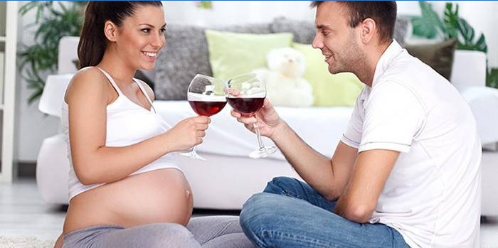 La donna incinta beve vino in compagnia di un uomo