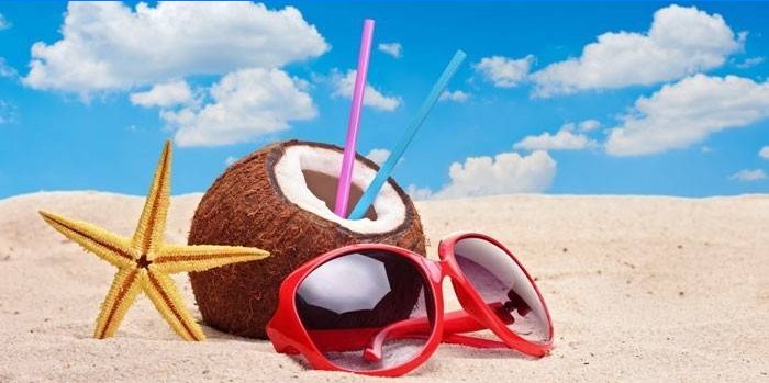 Cocco e bicchieri sulla sabbia