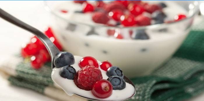 Yogurt con frutti di bosco freschi in un cucchiaio e una ciotola
