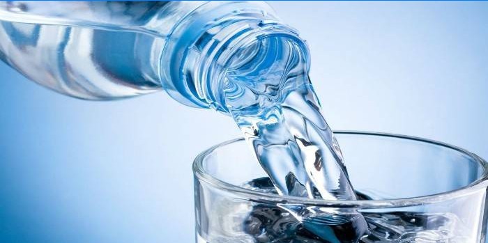 L'acqua di una bottiglia viene versata in un bicchiere