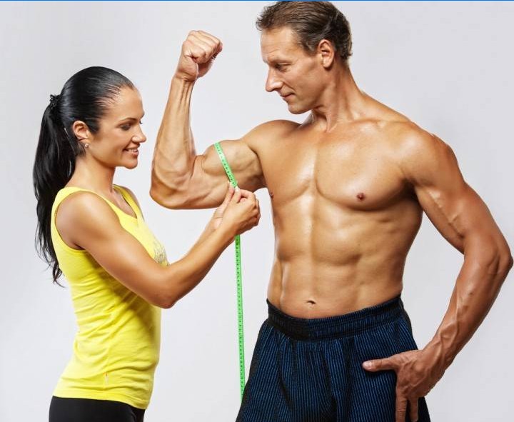 La ragazza misura la quantità di muscoli nel braccio di un uomo