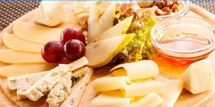 Piatto di formaggi con frutta, noci e miele.