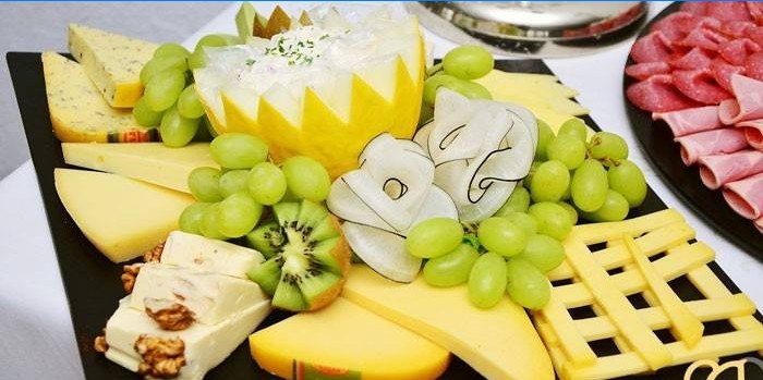 Piatto di formaggi con melone e uva