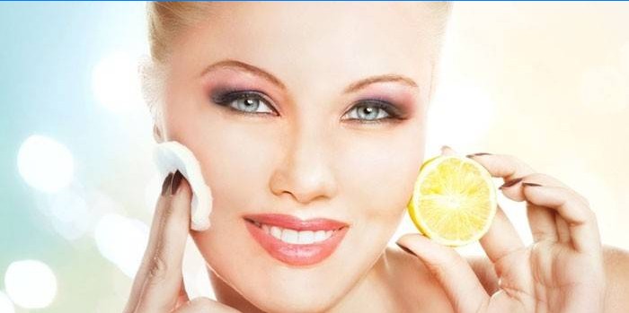 La donna si strofina il viso con il succo di limone