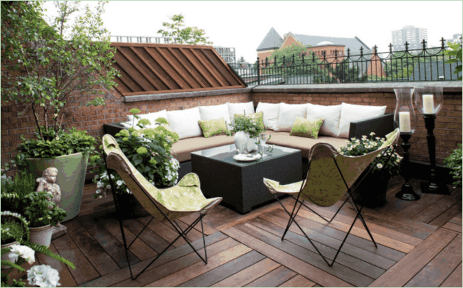 Il patio di una casa di campagna su una terrazza sul tetto: un divano ad angolo, poltrone e fiori Terrazza sul tetto di una casa di campagna - divano ad angolo, poltrone e fiori