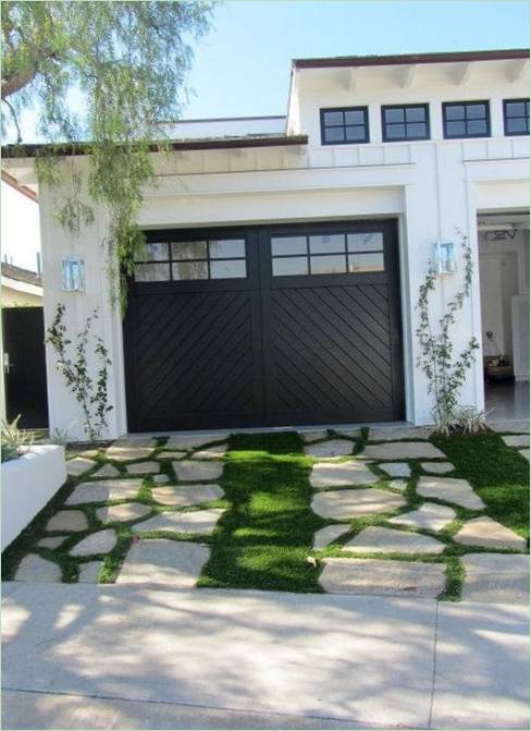 Un sentiero di erba verde e pietre davanti al garage Vialetto con erba verde e pietre davanti al garage