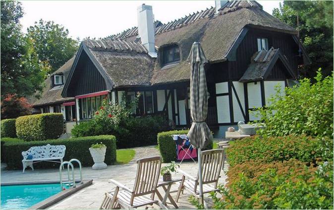 Un cottage a due piani con tetto di paglia